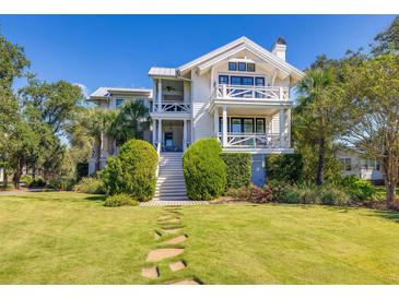 Stunning two-story white home with dual balconies, grand staircase, and lush lawn at 1302 Middle St, Sullivans Island, SC 29482