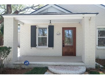 Charming front porch with a brick trim, a wooden front door, and an ADT security system sign for added peace of mind at 1637 Tatum St, Charleston, SC 29412