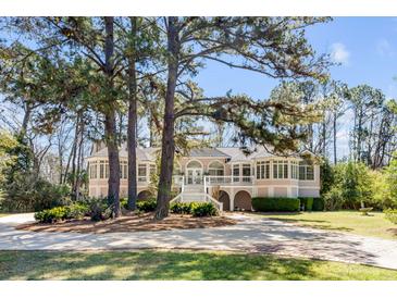 Stunning exterior elevation of home surrounded by mature trees and lush landscaping at 1988 Long Creek Rd, Wadmalaw Island, SC 29487