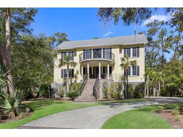 Stately two-story home boasts a charming front porch, upper balcony, and lush landscaping at 2440 Cat Tail Pond Rd, Seabrook Island, SC 29455