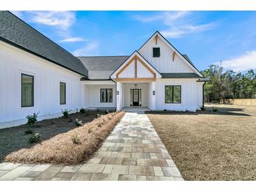 Charming exterior view of a modern farmhouse with a stone walkway and manicured landscaping at 4036 Azalea Farms Way, McClellanville, SC 29458