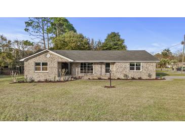 Charming brick home with a well-manicured lawn and mature trees against a clear blue sky at 5330 Waterview Dr, North Charleston, SC 29418