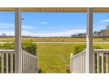 Inviting porch view reveals expansive grassy front yard and a picturesque landscape at 729 2Nd Bend Rd, Harleyville, SC 29448