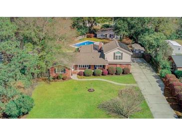 Stunning aerial view of a brick home with lush lawn, mature trees, and a sparkling pool, offering a private and serene oasis at 958 Mikell Dr, Charleston, SC 29412