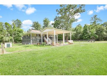 Sprawling property with a covered outdoor area, surrounded by lush greenery and a fenced yard at 13959 Cottageville Hwy, Cottageville, SC 29435