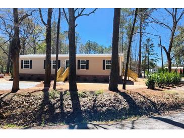 Charming single-story home featuring tan siding, dark shutters, and a wooden staircase leading to the front door at 413 Peacock Ln, Summerville, SC 29486
