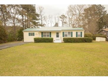Charming one-story home featuring a manicured lawn and a green metal roof at 424 Salley Ackerman Dr, Cottageville, SC 29435