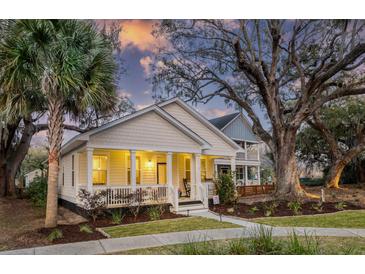 Charming yellow home with a welcoming front porch, beautiful landscaping, and mature trees at 5108 Celtic Dr, North Charleston, SC 29405