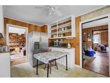 Cozy kitchen with wood paneling, white cabinets, stainless steel refrigerator, and a view into other rooms at 7560 Cottageville Hwy, Round O, SC 29474