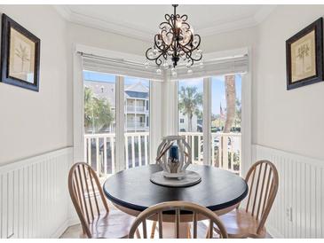 Bright breakfast nook with a decorative chandelier and a bay window overlooking the outdoor area at 9000 Palmetto Dr # G203, Isle of Palms, SC 29451