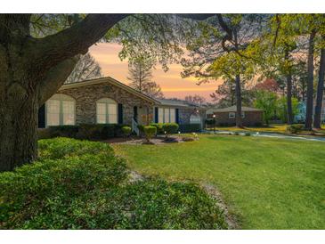 Charming brick home featuring lush landscaping, a well-manicured lawn, and mature trees, creating a welcoming curb appeal at 115 Clubhouse Rd, Summerville, SC 29483