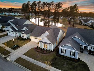 Scenic aerial view of a well-maintained neighborhood with homes surrounding a tranquil pond at sunset at 105 Bluff Isle Ct, Summerville, SC 29486
