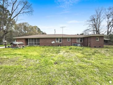 Exterior view of a brick house with a screened porch surrounded by a green lawn under a blue sky at 1393 Russellville Rd, Saint Stephen, SC 29479