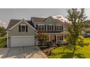 Charming two-story home featuring a welcoming front porch and well-manicured lawn and a two car garage at 144 Back Tee Cir, Summerville, SC 29485