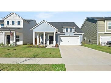 Charming single-Gathering home featuring a covered porch and a two-car garage on a well-manicured lawn at 173 Paddle Boat Way, Summerville, SC 29485