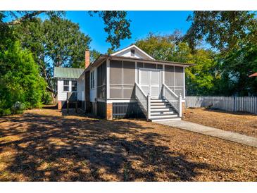 Charming single-story home with a screened-in porch and white picket fence, surrounded by lush greenery at 2314 Goldbug Ave, Sullivans Island, SC 29482