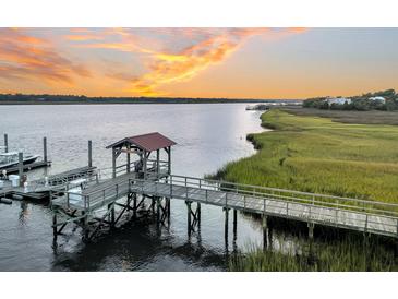 A wooden dock with a covered gazebo extends into the water at sunset, offering scenic waterfront views at 4247 Faber Place Dr # 5103, North Charleston, SC 29405