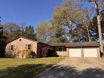 Charming brick home featuring a well-manicured lawn and an attached two car garage at 5310 Edith St, North Charleston, SC 29418