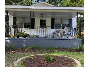 Charming front porch with black iron railing, plants, and seating area with cute cats enjoying the outdoor space at 5834 Beverly Dr, Hanahan, SC 29410