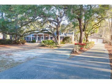 Charming brick home featuring a welcoming front porch and beautifully landscaped yard with mature trees at 10812 Dorchester Rd, Summerville, SC 29485