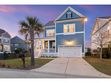 Charming two-story blue home with a white garage and inviting front porch at dusk at 1251 Weather Helm Dr, Mount Pleasant, SC 29466