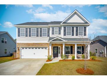 Charming two-story home with a combination of stone and white siding, complemented by a well-manicured lawn and a two-car garage at 2916 Cavalcade Cir, Johns Island, SC 29455