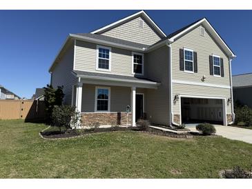 Charming two-story home with a well-manicured lawn, stone accents and an attached two car garage at 3059 Adventure Way, Ladson, SC 29456