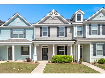 Charming townhome features colorful exteriors, a well-manicured lawn, and a covered front porch at 407 Stoneleigh Ln, Moncks Corner, SC 29461