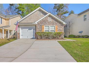Charming home featuring a stone facade, well-manicured lawn, and a garage with white doors at 108 Chemistry Cir, Ladson, SC 29456
