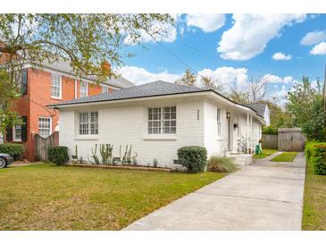Charming single-story white brick home with a well-manicured lawn and a paved driveway at 223 Grove St, Charleston, SC 29403