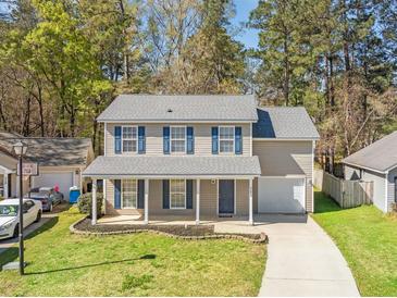 Charming two-story home with blue shutters, a welcoming front porch, and well-maintained landscaping at 115 Trickle Dr, Summerville, SC 29483
