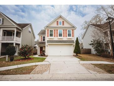 Charming two-story home with a well-manicured lawn and a two car garage with red shutters and beige colored siding at 2049 Maybelles Ln, Charleston, SC 29414
