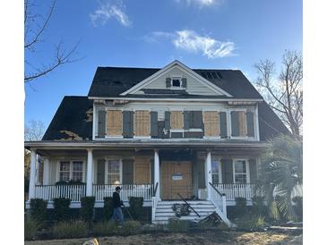 Two-story home with damaged roof and boarded windows at 3055 Yachtsman Dr, Mount Pleasant, SC 29466