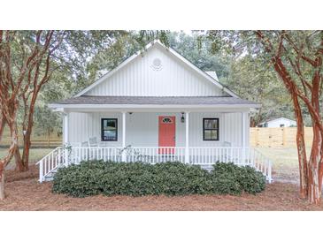 Charming cottage-style house with a porch, coral front door, and white exterior at 3166 Edenvale Rd, Johns Island, SC 29455