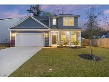 Charming two-story home with a well-manicured lawn, attached garage, and classic architectural details at dusk at 3215 Safe Harbor Way, Charleston, SC 29414