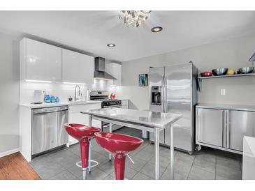 Modern kitchen with stainless steel appliances, sleek white cabinets, and a center island with red bar stools at 4445 Old Park Rd, North Charleston, SC 29405