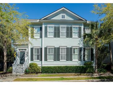 Charming two-story home featuring light blue siding, black shutters, and a welcoming front porch, enhanced by lush landscaping at 740 Stucco Ln, Mount Pleasant, SC 29464