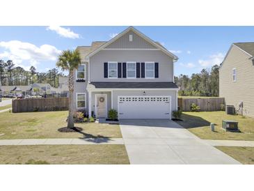 Charming two-story home with a well-maintained lawn, a palm tree, and an attached two-car garage at 101 Corvus Ct, Summerville, SC 29486