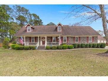 Charming brick home featuring dormer windows, manicured landscaping, and a welcoming front porch at 117 Hartin Blvd, Summerville, SC 29486