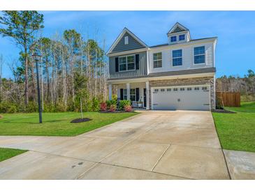 Charming two-story home with a well-manicured lawn and a two-car garage with a beautiful blue sky overhead at 204 Torslanda Ln, Summerville, SC 29486