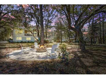 Relaxing fire pit area with Adirondack chairs and a view of the home's exterior at dusk at 5208 Holly Forest, Hollywood, SC 29449