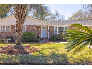 Charming brick home with a well-manicured lawn and mature palm trees in a sunny front yard at 689 Port Cir, Charleston, SC 29412