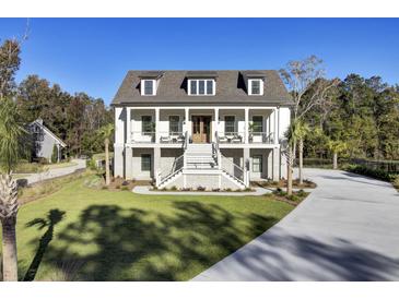 Elegant two-story home with a grand staircase, double balconies, and lush green lawn at 8638 Scottish Troon Ct, North Charleston, SC 29420