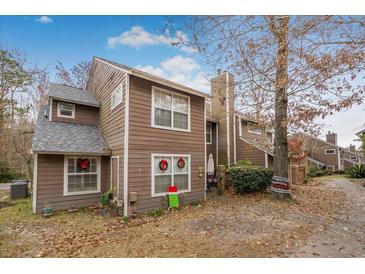 Charming brown two-story home with white trim, a chimney, and windows decorated with Christmas wreaths at 120 Luden Dr # C, Summerville, SC 29483