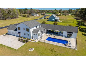 Stunning aerial view of a sprawling white farmhouse with a pool and lush green lawn at 161 Ryefield Ln, Ridgeville, SC 29472