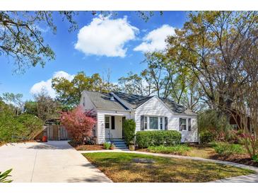 Charming single-story home with a manicured lawn, mature landscaping, and a paved driveway under a blue sky at 4 St Teresa Dr, Charleston, SC 29407