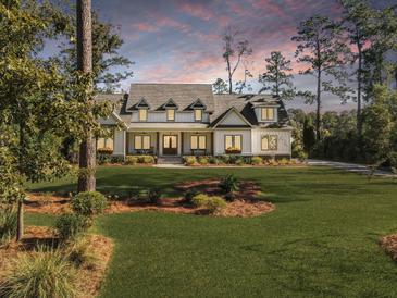 Stunning exterior showcasing a beautifully landscaped front yard and charming two-story home at sunset at 4086 Lady Banks Ln, Ravenel, SC 29470