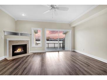 Bright living room featuring a fireplace, ceiling fan, wood floors, and balcony access with a beautiful sunset view at 4913 Lake Palmetto Ln, North Charleston, SC 29418