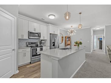 Bright kitchen with white cabinets, stainless steel appliances, and a large center island with quartz countertops at 500 Bucksley Ln # 308, Charleston, SC 29492