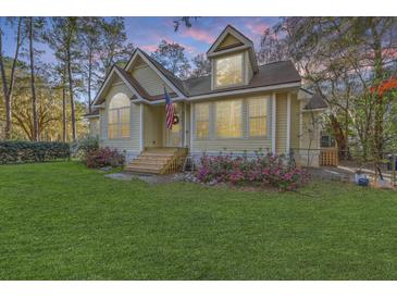 Charming exterior with lush lawn, blossoming flowers, and an American flag displayed at 5758 Chisolm Rd, Johns Island, SC 29455